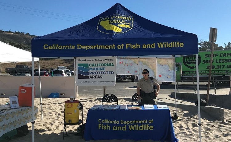 Photo of a California Department of Fish and Wildlife booth at the beach promoting Marine Protected Areas.